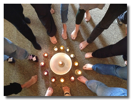 Women's bare feet in circle, pointing at candles