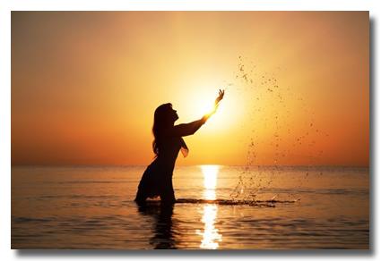 Woman splashing water at sunset